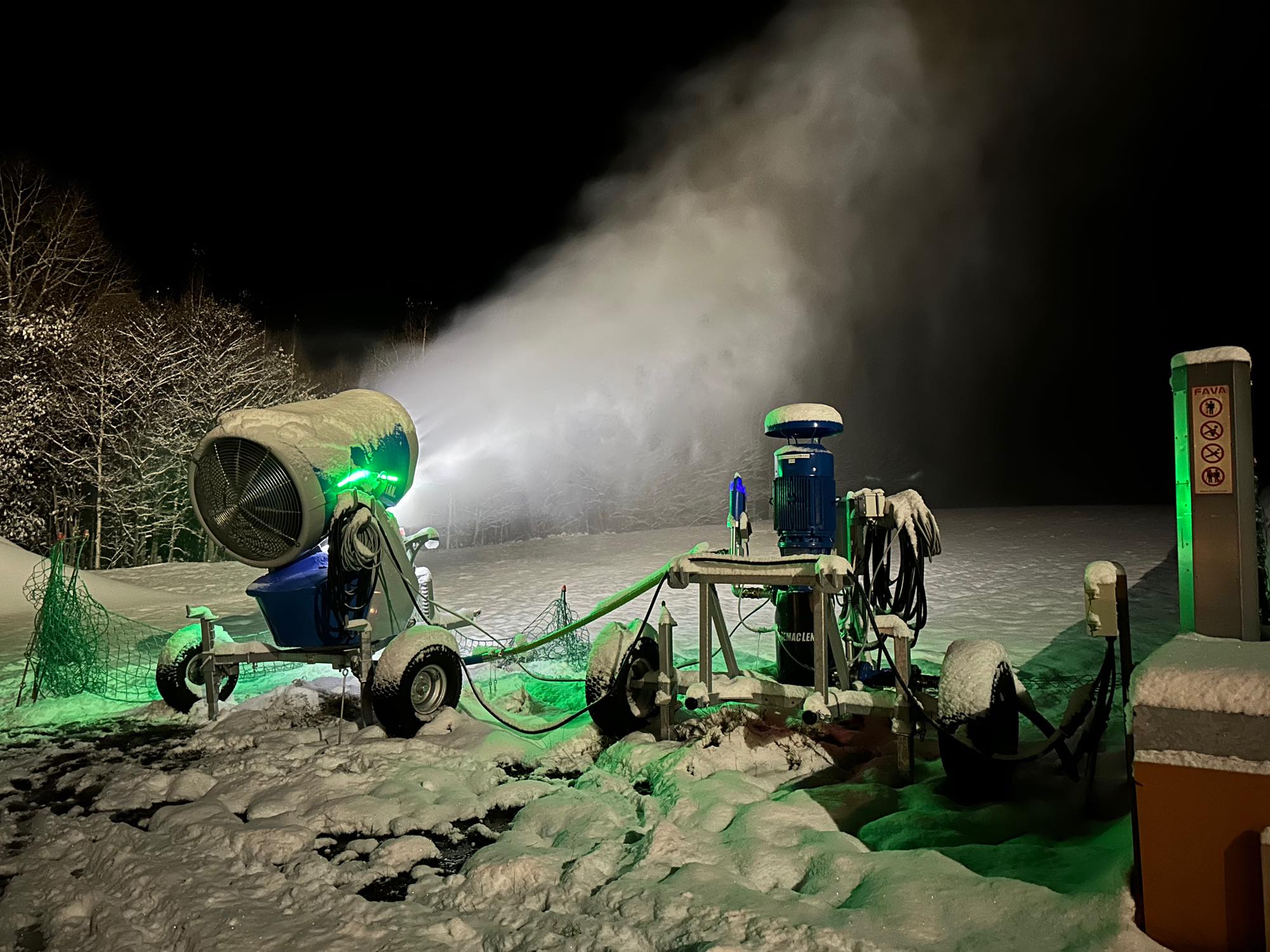 夜間に稼働する人工降雪機が雪を吹き出す様子