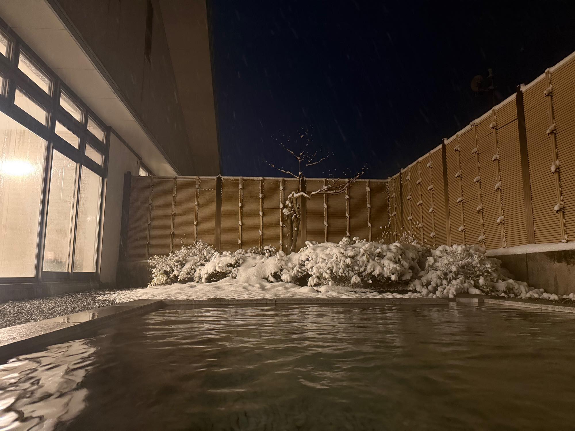 雪が積もる夜の露天風呂と湯面