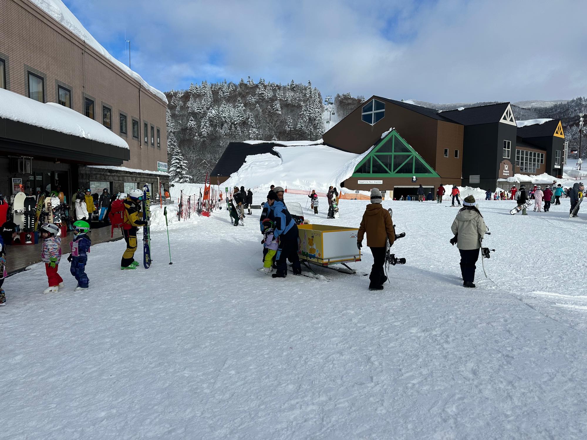 雪のスキー場のベースエリアを行き交うスキーヤーとスノーボーダー