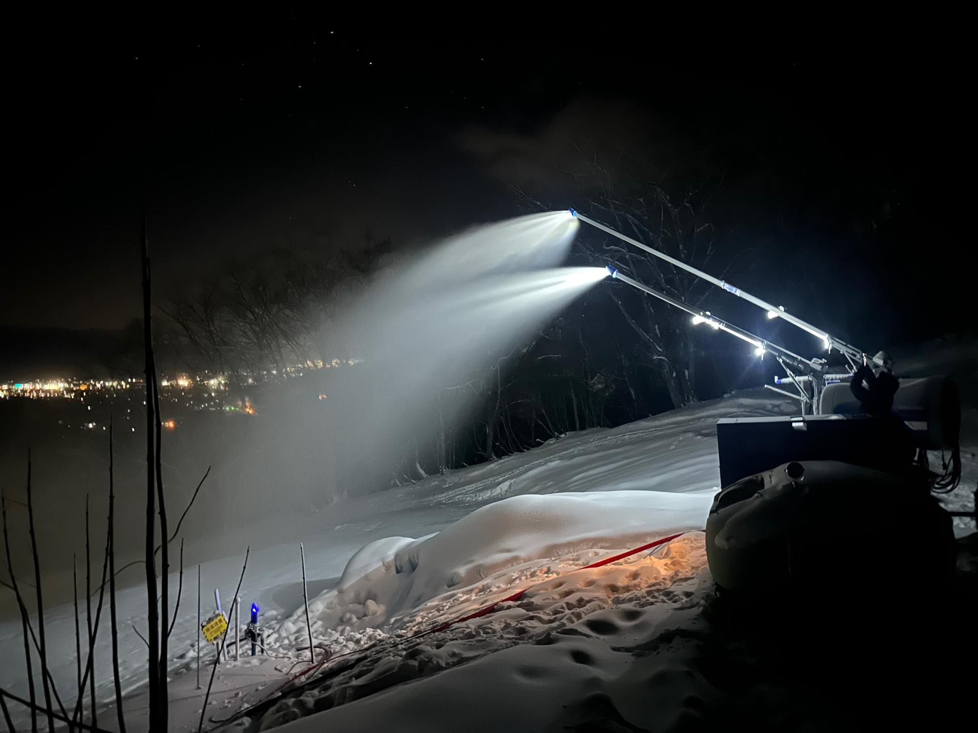 夜の斜面で稼働する人工降雪設備