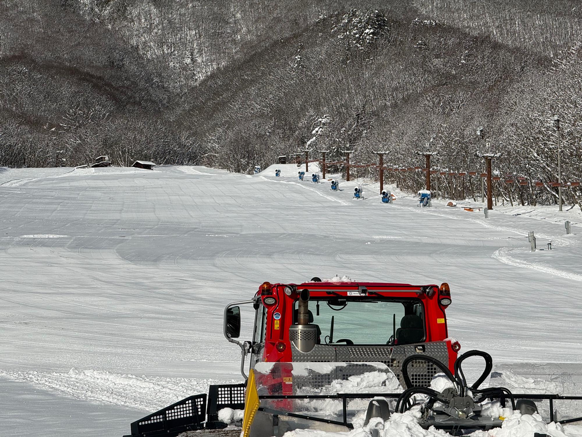 ゲレンデにある赤い圧雪車と整った雪面