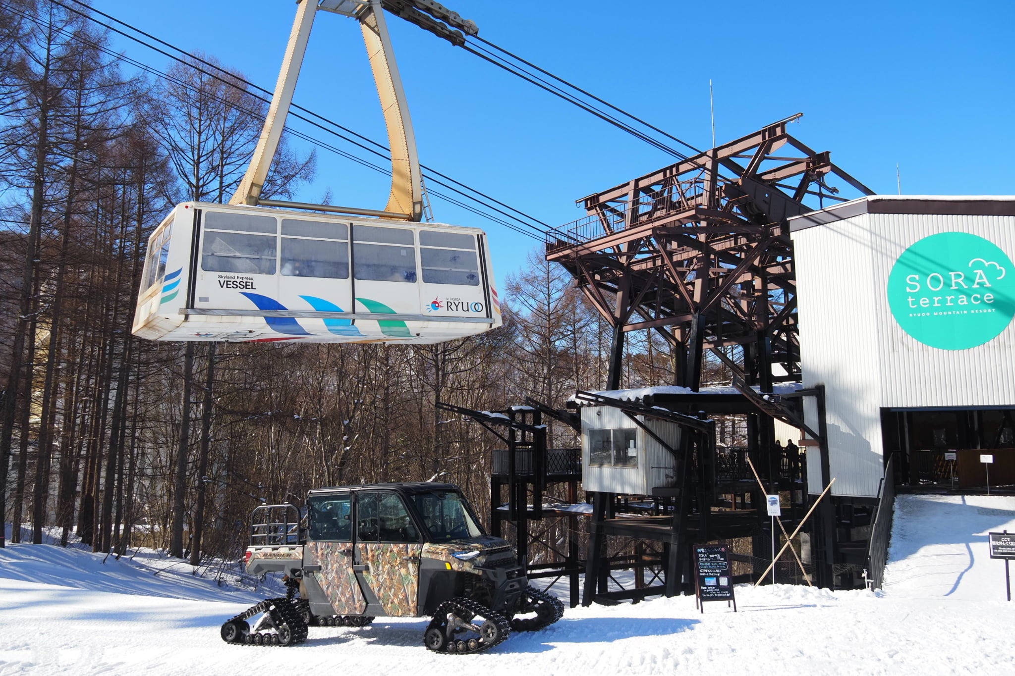 竜王のロープウェイ山麓駅前に停車する雪上バギーと大型ロープウェイ