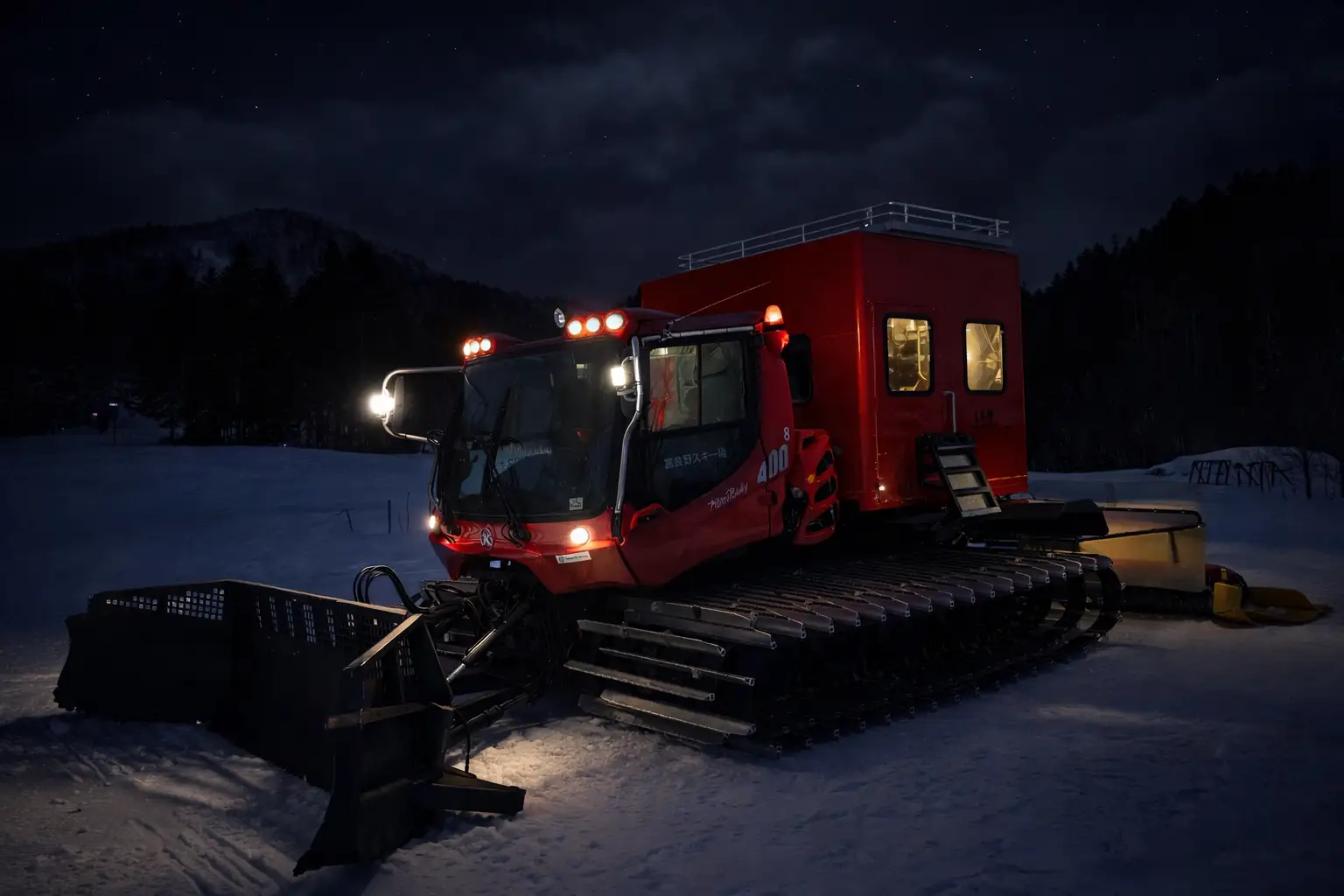 夜のゲレンデを走るキャビン付き圧雪車