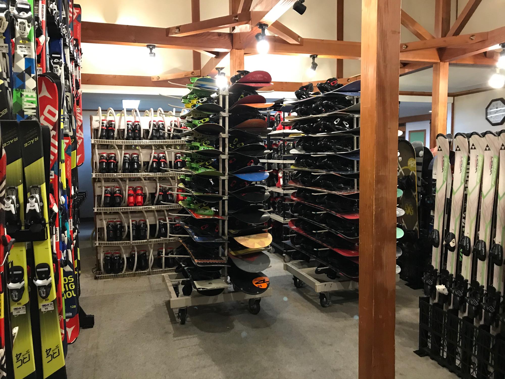ラックにスノーボードやスキー板、ブーツが並ぶ用具レンタルの店内